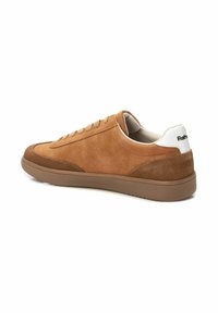 Zapatilla de ante marrón con textura suave, suela de goma y panel en el talón blanco en contraste. Presenta un cierre clásico con cordones y un diseño minimalista.