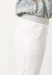Witte broek met een gestructureerde tailleband met grijze strepen, zijzakken en een aansluitend ontwerp, met een soepele stof die aan katoen doet denken.