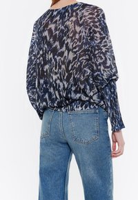 Lichte blouse in marineblauw en zilver met een patroon, met een losse fit, vleermuismouwen en een gerimpelde zoom, gecombineerd met hoge taillejeans.