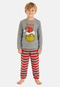 Maglietta da pigiama a maniche lunghe grigia con grafica "Feelin' Grinchy". Pantaloni da pigiama a strisce rosse e grigie. Tessuto morbido, vestibilità ampia e design leggero.