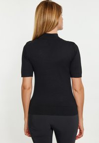 Top scurt din tricot negru, cu un design ajustat, textură canalată și decolteu rotund. Fără modele vizibile sau detalii din metal.
