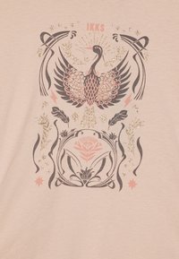 Lys rosa t-skjorte med et sentralt sort og gull påfugldesign, omringet av blomstermotiver og dekorative elementer i matchende farger.