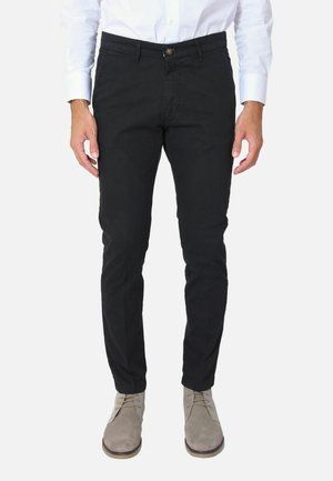 Pantaloni neri in cotone con vestibilità slim, caratterizzati da una chiusura con bottone e tasche. Abbinati a stivali grigi in suede con lacci.