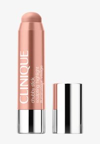 Enlumineur sculptant Clinique Chubby Stick dans un tube rose doré avec un capuchon argenté, le capuchon posé à côté du stick.