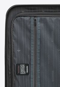 Interno di una valigia grigia espandibile con una tasca in rete e diversi scomparti con zip, realizzato in un tessuto testurizzato e con un motivo stampato.