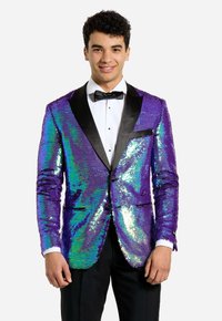 Giacca da smoking a paillettes viola e verdi con revers neri, chiusura con un solo bottone e tasche laterali; indossata sopra una camicia bianca e un papillon nero.