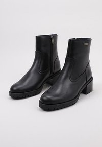 Botas de tobillo de piel negra con cierre de cremallera, puntera redonda, suela texturizada y tacón grueso. Acabado suave con un sutil logo de acento.