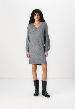 Gray knitted dress with a V-neck, long sleeves, and ribbed hem, paired with black leather knee-high boots featuring side zippers.