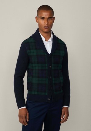 Cardigan lavorato a maglia con un design a quadri blu navy e verde, colletto scialle e cinque bottoni. Presenta maniche e orlo a coste per aggiungere texture.