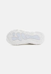 Hvid sneakersål med tekstureret gummi, der har et bølget design og cirkulære mønstre for godt greb. Bemærkelsesværdig logo detalje i lyseblå.