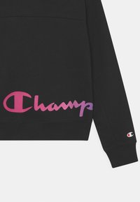 Sudadera negra con un gran logotipo degradado en rosa y morado, con puños y dobladillo acanalados. Pequeño parche con logotipo cerca de la manga. Material de algodón suave.