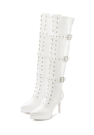White patent leather knee-high boots with a pointed toe, lace-up front, and three buckle straps; features a high stiletto heel and platform sole.