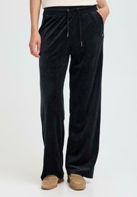 Zwarte corduroy broek met een relaxed fit, voorzien van een trekkoord in de taille, zijzakken en een subtiele verticale ribbelstructuur.