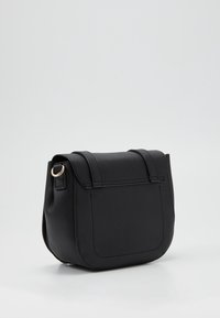 Borsa a tracolla in pelle nera con superficie texturizzata, forma rettangolare, chiusura a pattina e un anello metallico decorativo sul lato.