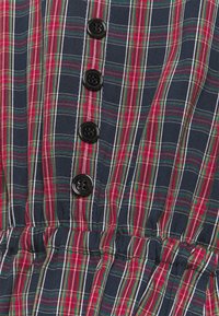 Marinblå rutig klänning med röda och gröna linjer, svarta knappar och en elastisk midja för form och passform.