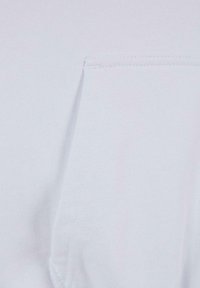 Camiseta de algodón blanca con un bolsillo en el lado izquierdo del pecho, textura suave y acabado liso con costuras visibles alrededor del bolsillo.