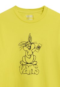 Žluté bavlněné tričko s černou grafikou králíka, který drží ovladač, a textem "vans" pod designem. Klasický střih.