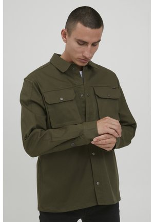 Olive green button-up shirt made of sturdy fabric with two chest pockets and snap buttons, featuring a classic collar and long sleeves.