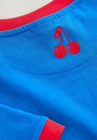 Baumwoll-T-Shirt mit blauem Körper, rotem Kragen und roten Akzenten an den Ärmeln. Auffälliges rotes gesticktes Kirschdesign auf dem Rücken in der Nähe des Kragens.