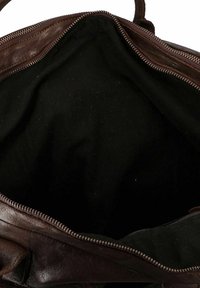 Sac en cuir marron ouvert avec fermeture éclair métallique visible et doublure intérieure en tissu noir vide.