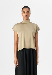 Top a maniche corte con collo alto in tessuto beige chiaro dalla texture liscia; vestibilità ampia, drappeggio sull'orlo, abbinato a una gonna nera.