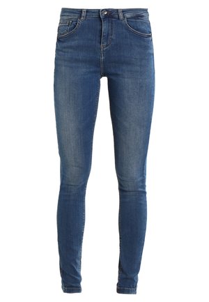 Lieknos džinsai vidutinio mėlynumo džinsinio audinio, išsiskiriantys aukštu liemeniu, penkių kišenių dizainu ir subtiliu nublukimu, suteikiančiu tekstūrą. Klasikinis mygtuko ir užtrauktuko uždarymas.