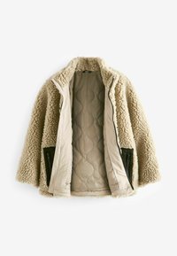 Beige Kunstpelzjacke mit gestepptem Innenfutter und schwarzen Reißverschlusstaschen an den Seiten, mit hohem Kragen und lockerer Passform.