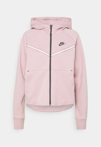 Felpa Nike rosa con zip. Presenta strisce a zigzag bianche sul petto, tasche a marsupio e polsini a coste. Tessuto morbido.