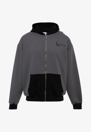 Felpa grigia con zip, dotata di cappuccio e tasca nera. Tessuto morbido, polsini e orlo a costine, con un piccolo logo nero sul petto.