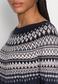 Maglione a maglia navy con motivi geometrici in rosa, grigio e bianco. Collare a girocollo a costine e dettagli in tessuto testurizzato.