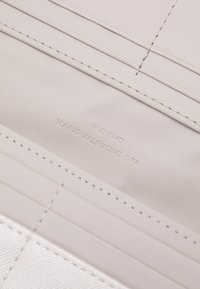 Cream leather wallet interior with embossed logo details. Features card slots, smooth texture, and contrasting stitching.