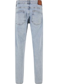 Jeans de mezclilla de color azul claro con corte recto, cintura a media altura, dos bolsillos traseros y una etiqueta de cuero marrón en la cintura.