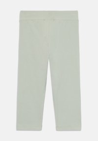 Leggings vert clair en matériau doux, avec un design simple, une taille élastique et des détails de couture subtils.