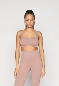 Αθλητικό σουτιέν σε ανοιχτό ροζ με ριμπ υφή, φαρδιές τιράντες, στρογγυλή λαιμόκοψη, και ταιριαστό κολάν με ψηλή μέση και απαλή υφή.