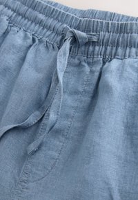 Pantaloncini in lino azzurro chiaro con vita elastica e coulisse. Tessuto liscio con dettagli di cuciture visibili.