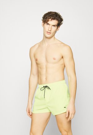 Bañador verde lima con un cordón negro en contraste, que presenta una cinturilla elástica y un pequeño logo negro en un lateral.