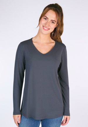 Langarm-V-Ausschnitt-Shirt in Dunkelgrau, aus weichem Stoff gefertigt. Hat eine lockere Passform und einen geraden Saum, kombiniert mit blauen Jeans.