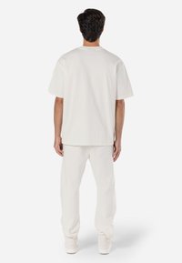 Camiseta de algodón blanca con un diseño relajado, acompañada de pantalones de chándal ajustados a juego. Textura suave y diseño sencillo. Color brillante.
