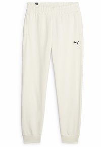 Pantalones de chándal color crema hechos de una tela suave, con cintura elástica, bolsillos laterales y un pequeño logo negro en el muslo izquierdo.