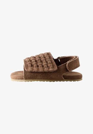 Brun åben sandal med en struktureret bred rem og justerbar bagrem på en flad sål.