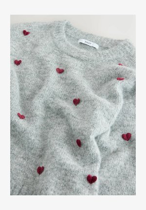 Világosszürke pulóver kellemes tapintással, piros hímzett szívecskékkel szétszórva a szöveten. A címke a nyaklánál „NEXT” feliratú.