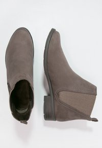 Braune Wildleder-Stiefeletten mit elastischen Seitenbesätzen im Fischgrätmuster. Niedriger Blockabsatz und rundes Zehen-Design.