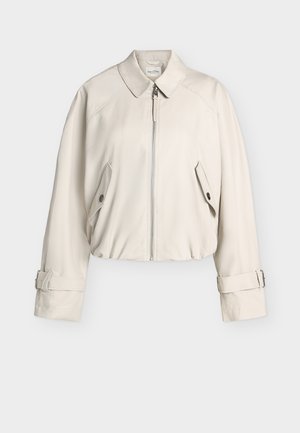 Ανοιχτό μπεζ ζακέτα με φερμουάρ, γιακά, τσέπες με καπάκι και κουμπιά, και ρυθμιζόμενες λουρίδες με αγκράφα στους μανσέτες.