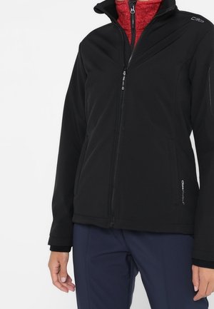 Zwarte softshell jas met hoge kraag, voorritssluiting en ritszakken. Heeft een gestructureerde rode voering en logo-detail op de schouder.