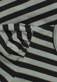 Svart och grönrandig tyg med tunna gyllene trådaccenter, med en mjuk, texturerad yta och samlad detalj.