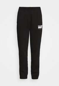 Schwarze Jogginghose aus Baumwollmischung, mit elastischem Bund und Bündchen, und einem weißen Logo, das am linken Oberschenkel aufgedruckt ist.