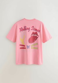 Růžové tričko s textem "Rolling Stones", otevřenou pusou se červeným bodavým jazykem, žlutými a modrými grafickými prvky, a nápisy "World Tour 94" a "Voodoo Lounge."