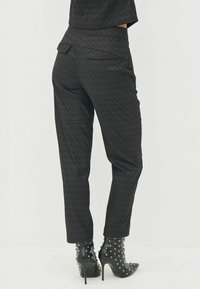 Zwarte textuur broek met een op maat gemaakte pasvorm, met achterzakken en diagonale naden, gecombineerd met zwart gestepte haklaarzen.