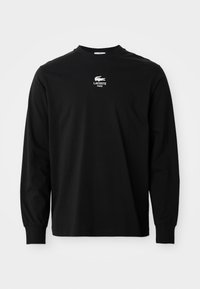 Schwarzes Langarm-T-Shirt aus Baumwolle mit Rundhalsausschnitt und gesticktem weißen Lacoste-Logo auf der Brust. Einfaches, klassisches Design.