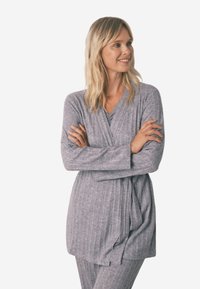 Ensemble de loungewear gris à côtes, composé d'un haut à manches longues croisé avec une taille à nouer, associé à un pantalon assorti, fabriqué à partir d'un tissu doux et texturé.